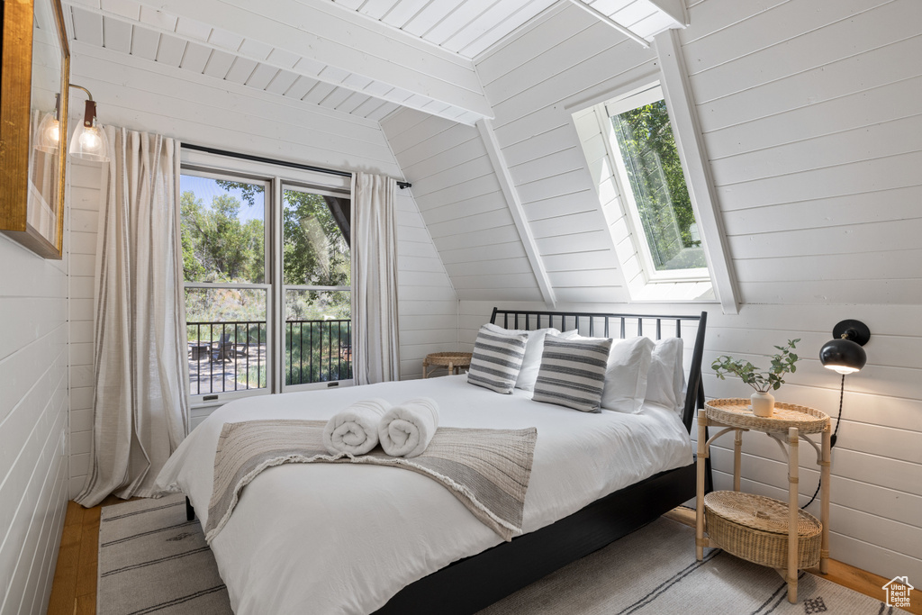 Bedroom with multiple windows, wood finished floors, vaulted ceiling, a skylight, and wooden ceiling