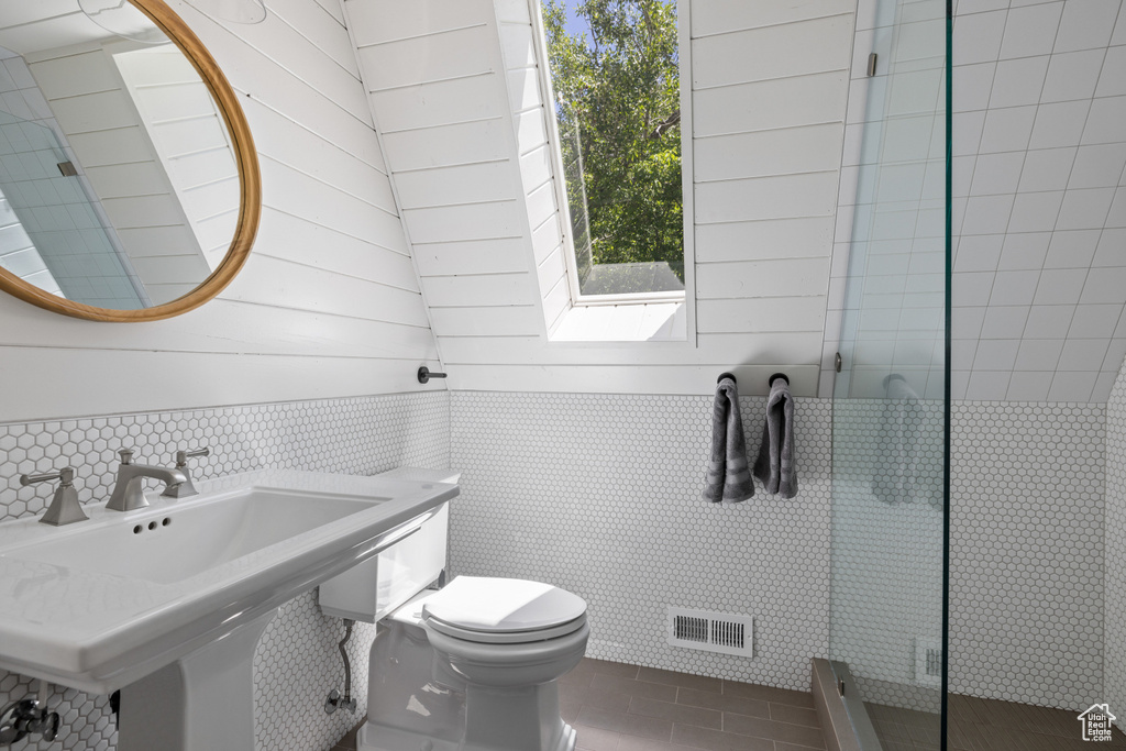 Bathroom with tile patterned flooring, tiled shower, and tile walls