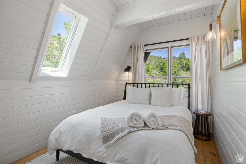 Bedroom with a skylight, wood finished floors, wooden walls, and wooden ceiling