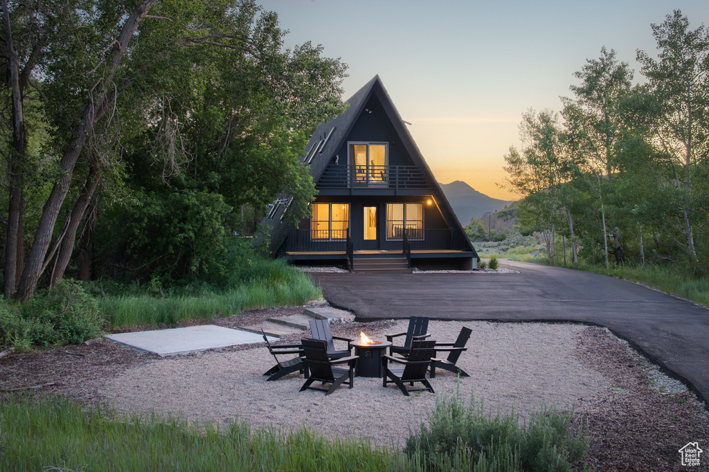 Back of property at dusk featuring a fire pit and a balcony