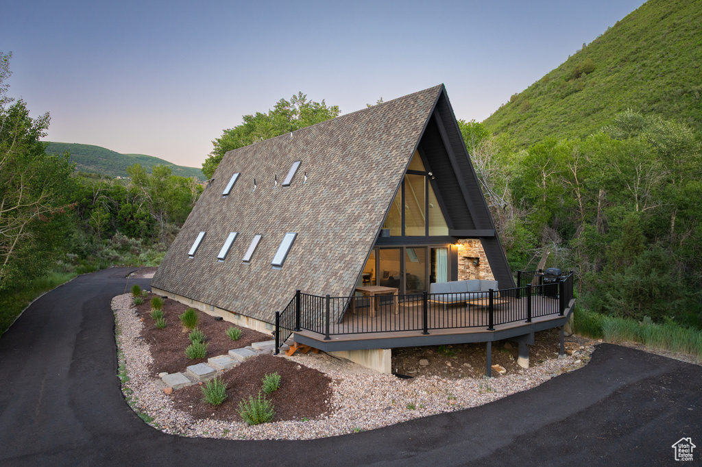 A-frame home featuring a deck with mountain view and a shingled roof