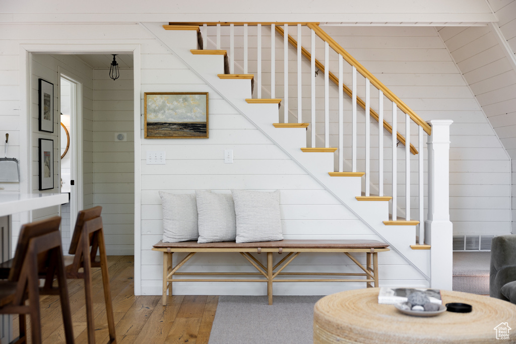 Staircase with hardwood / wood-style floors and wood walls