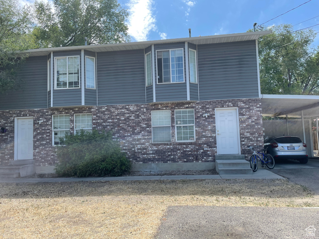 View of front of property with entry steps, an attached carport, brick siding, and asphalt driveway