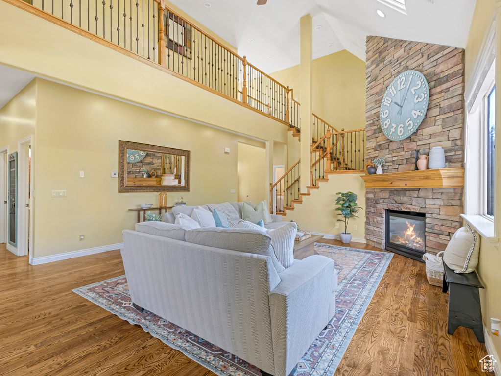 Living area with high vaulted ceiling, wood finished floors, a fireplace, and stairs