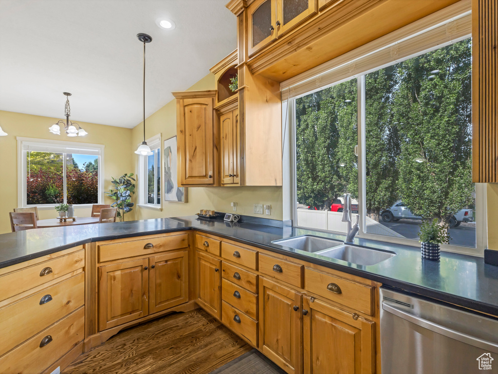Kitchen featuring stainless steel dishwasher, dark countertops, dark wood-style floors, a chandelier, and a peninsula