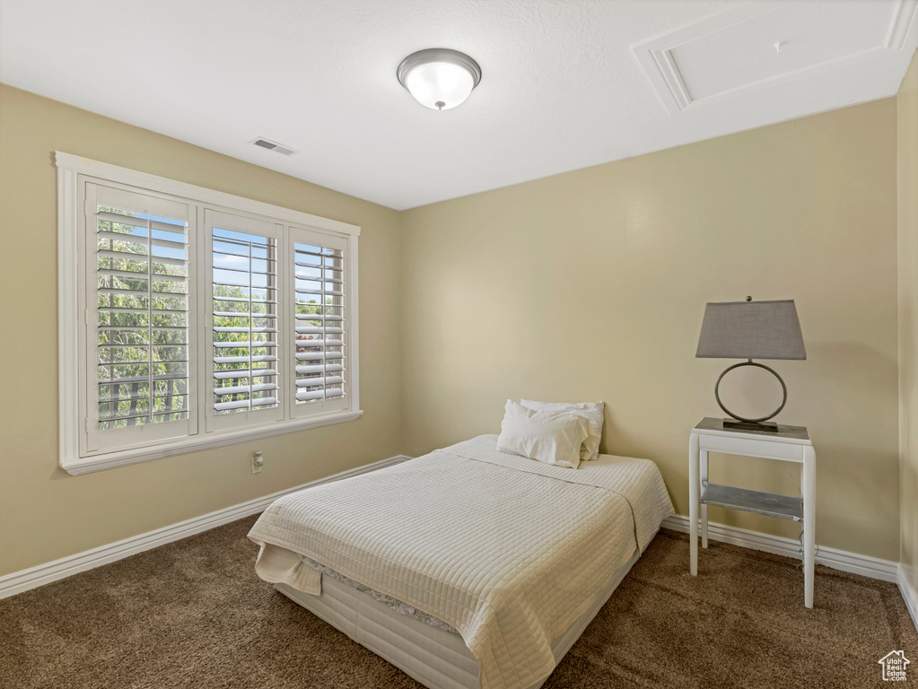 Carpeted bedroom with attic access and baseboards