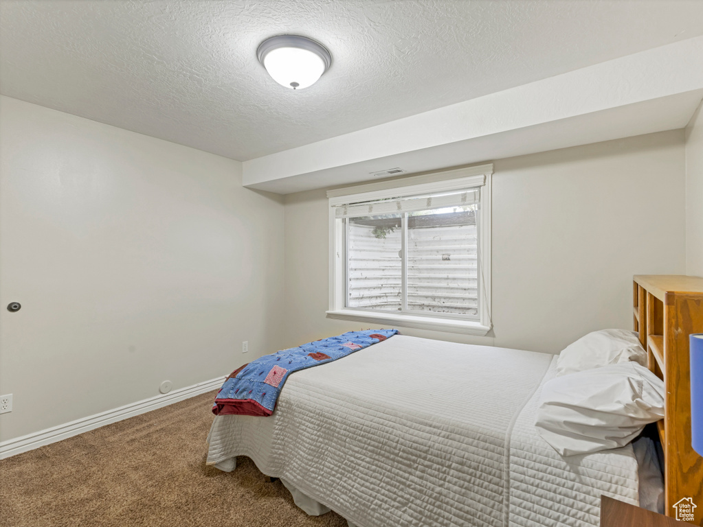 Carpeted bedroom with a textured ceiling and baseboards