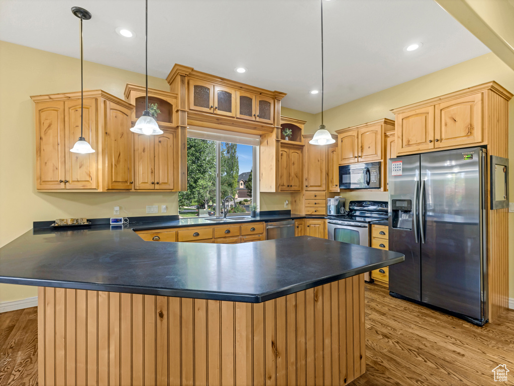 Kitchen featuring appliances with stainless steel finishes, dark countertops, wood finished floors, and recessed lighting