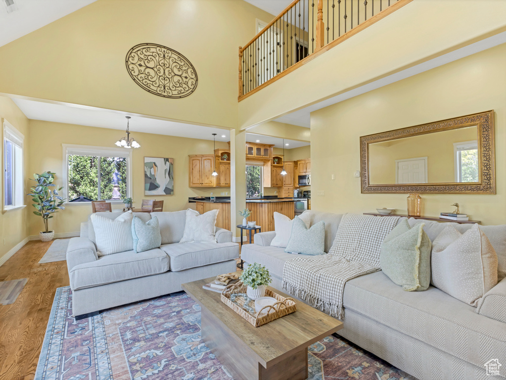Living area with a chandelier, light wood-style floors, and a high ceiling