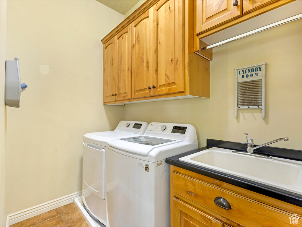 Laundry area with washer and clothes dryer, cabinet space, and light tile patterned floors