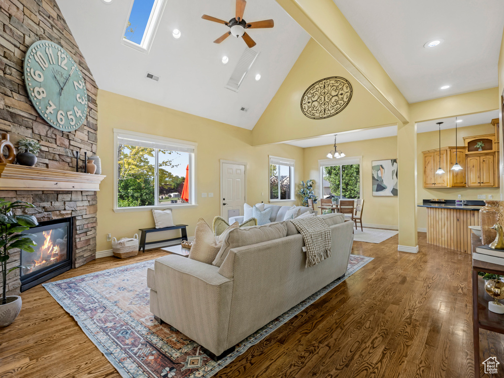 Living area featuring high vaulted ceiling, a ceiling fan, wood finished floors, a stone fireplace, and recessed lighting