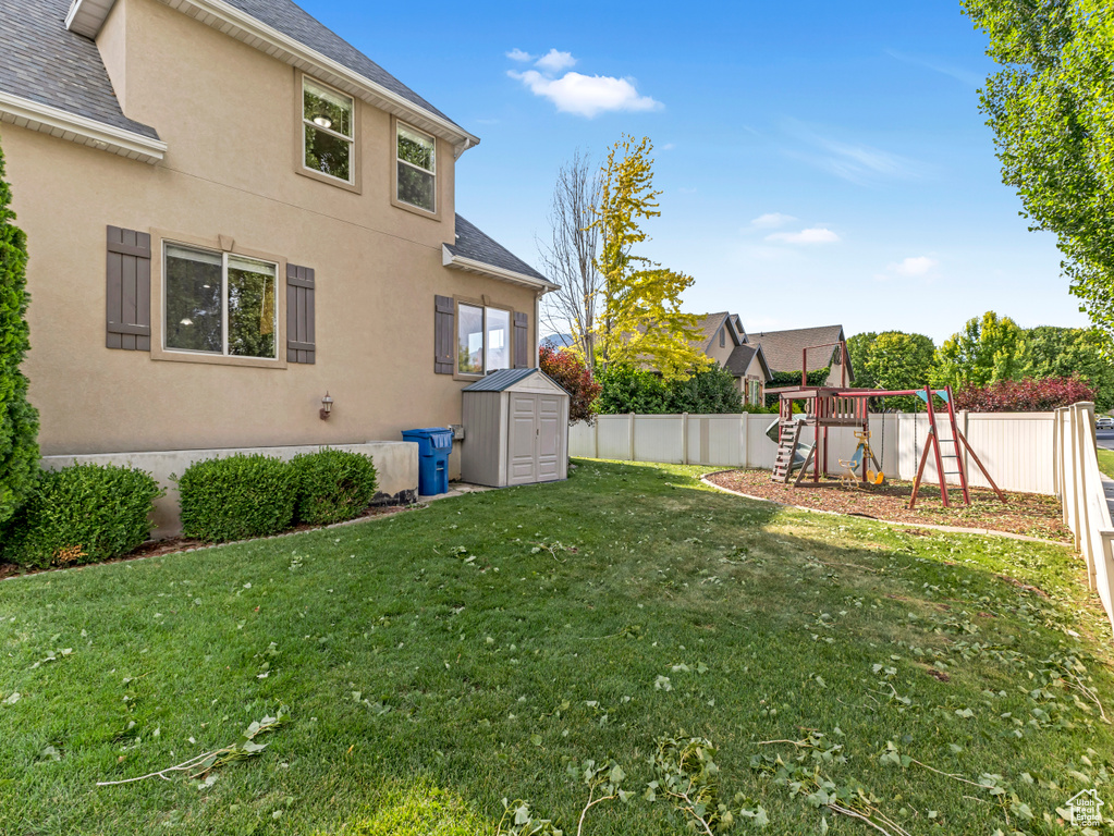 Fenced backyard featuring a storage shed and a playground