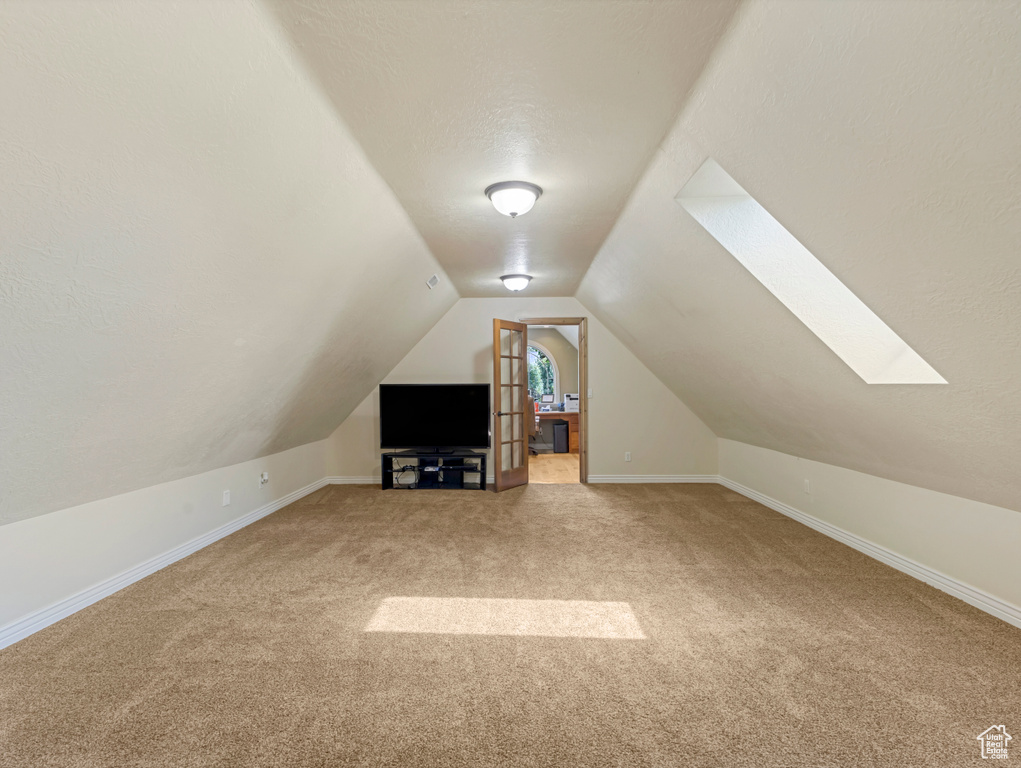 Bonus room featuring carpet floors, a skylight, and lofted ceiling