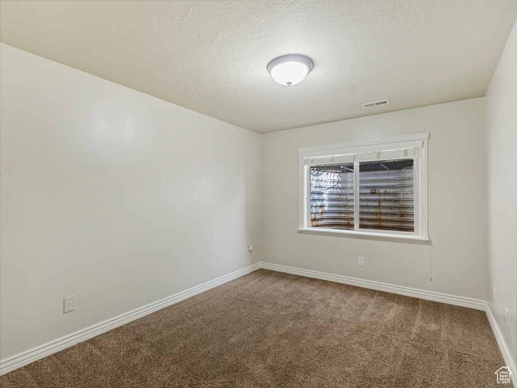 Carpeted empty room with baseboards and a textured ceiling
