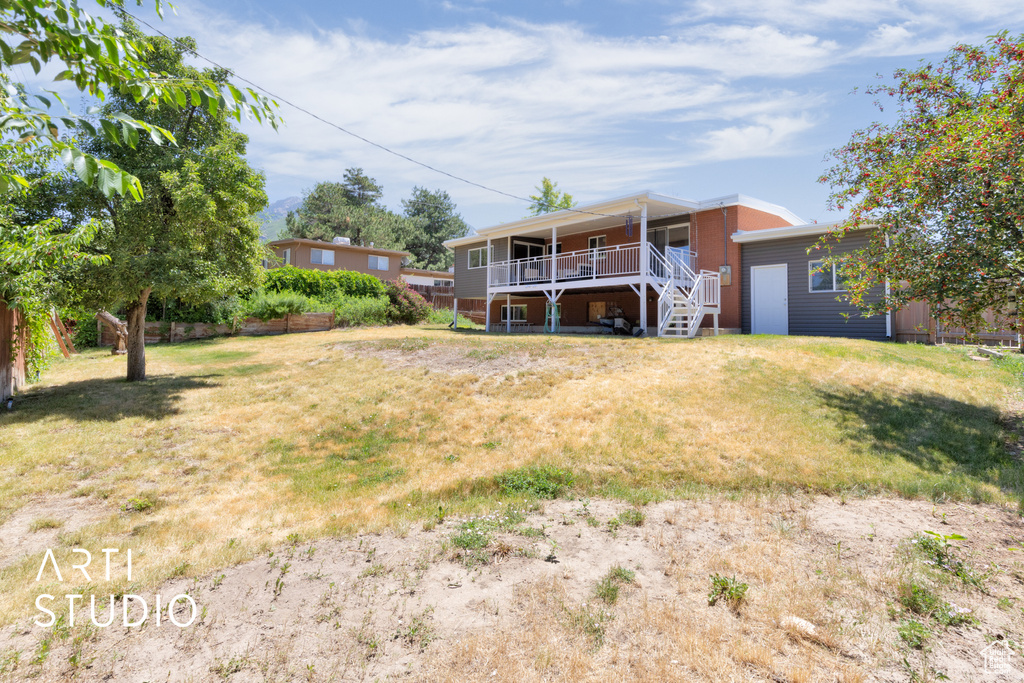 Back of property featuring stairway, a lawn, and a wooden deck