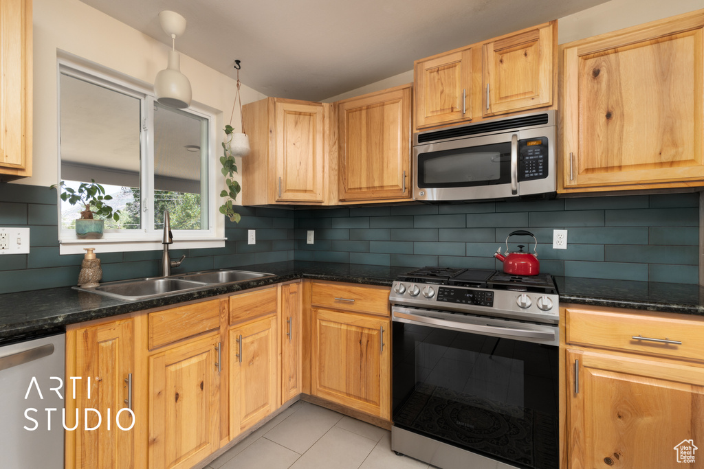 Kitchen with appliances with stainless steel finishes, light tile patterned floors, tasteful backsplash, and light brown cabinets