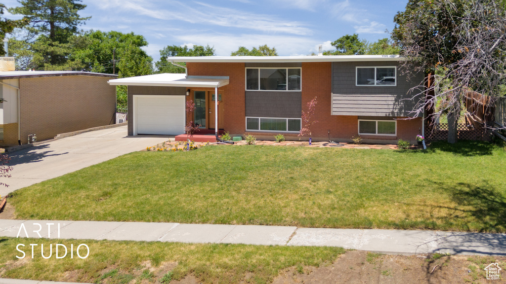 View of front of property featuring a garage, concrete driveway, a front lawn, and brick siding