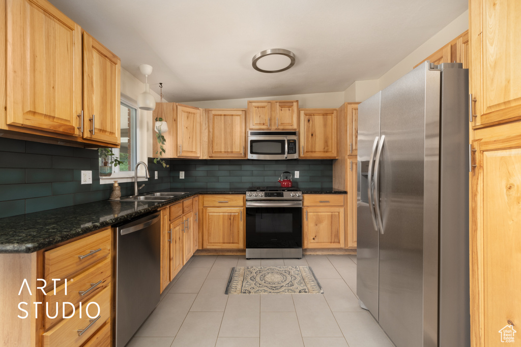 Kitchen with stainless steel appliances, tasteful backsplash, light brown cabinetry, and lofted ceiling