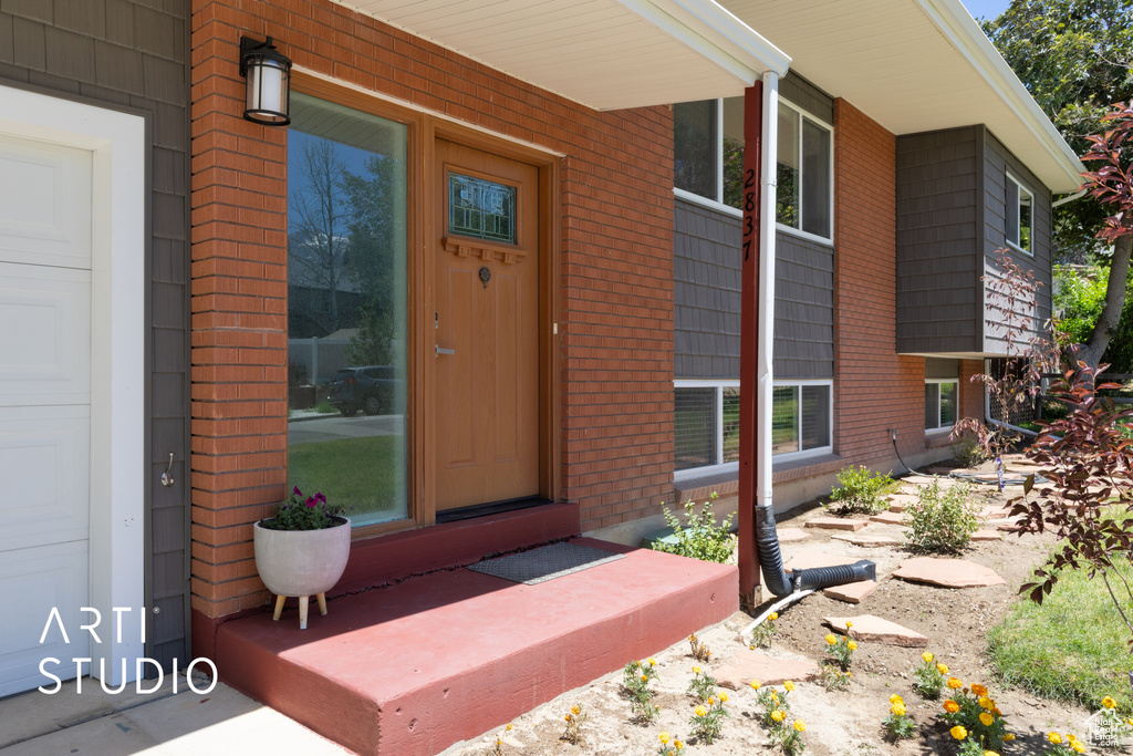 View of exterior entry with a porch and brick siding