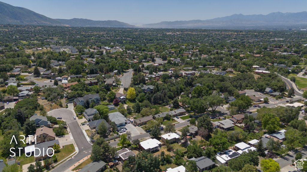 Aerial view of property and surrounding area featuring a mountainous background and nearby suburban area