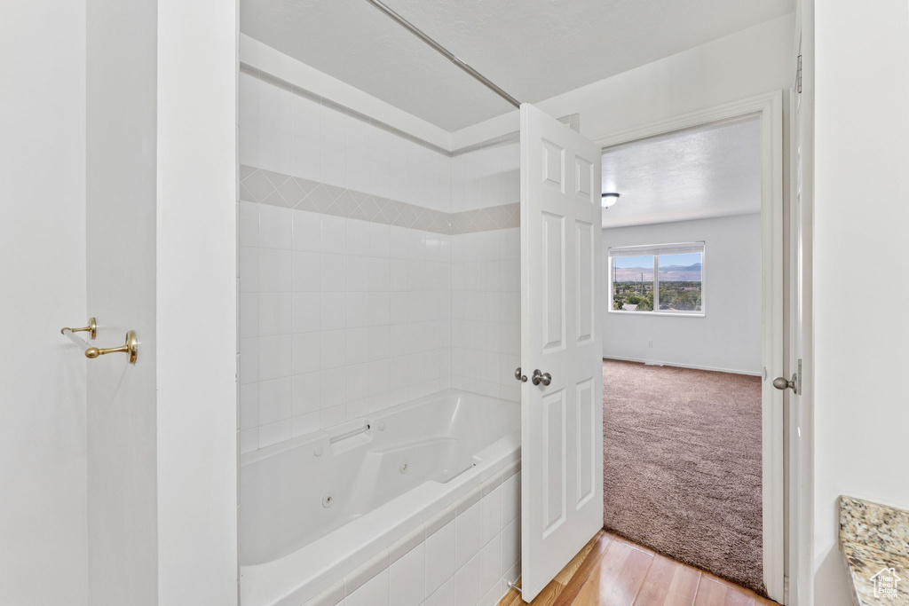 Full bathroom featuring a combined bath / shower with jetted tub and wood finished floors