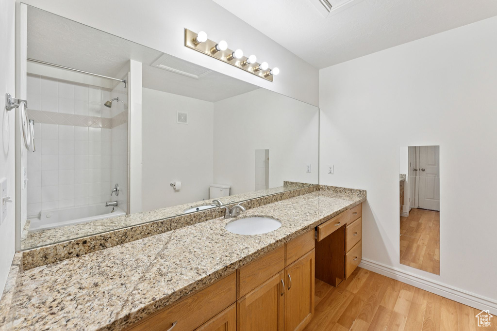 Full bathroom with wood finished floors, vanity, and washtub / shower combination