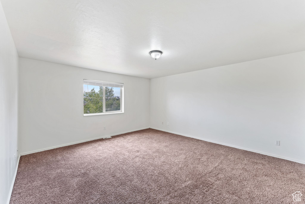 Carpeted spare room with baseboards