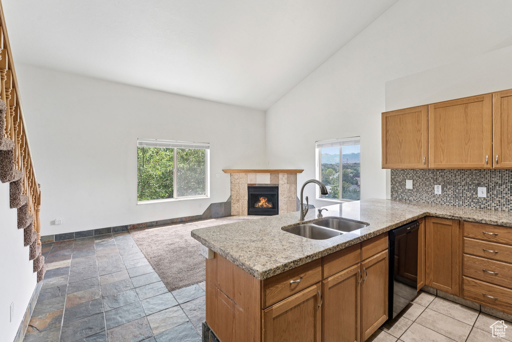 Kitchen with backsplash, dishwasher, a tiled fireplace, a peninsula, and high vaulted ceiling