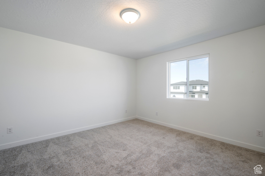 Empty room featuring carpet flooring and a textured ceiling