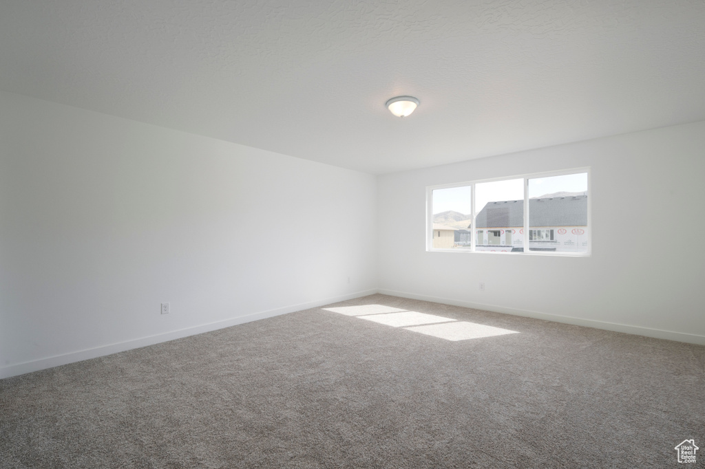 Carpeted spare room featuring baseboards