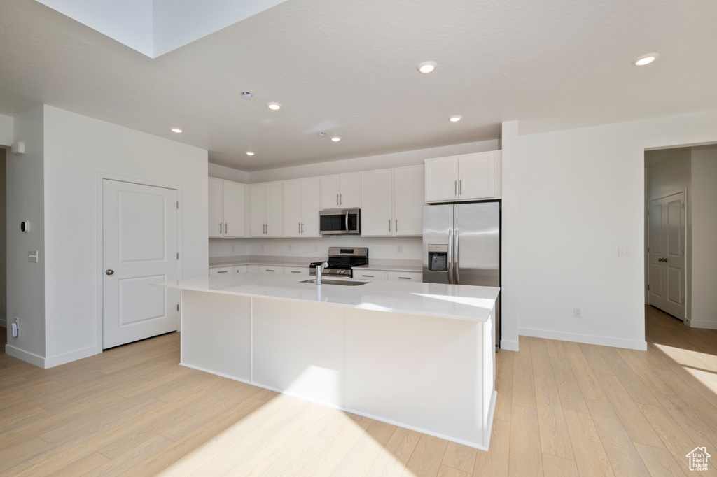 Kitchen with appliances with stainless steel finishes, light countertops, light wood-style flooring, white cabinets, and recessed lighting