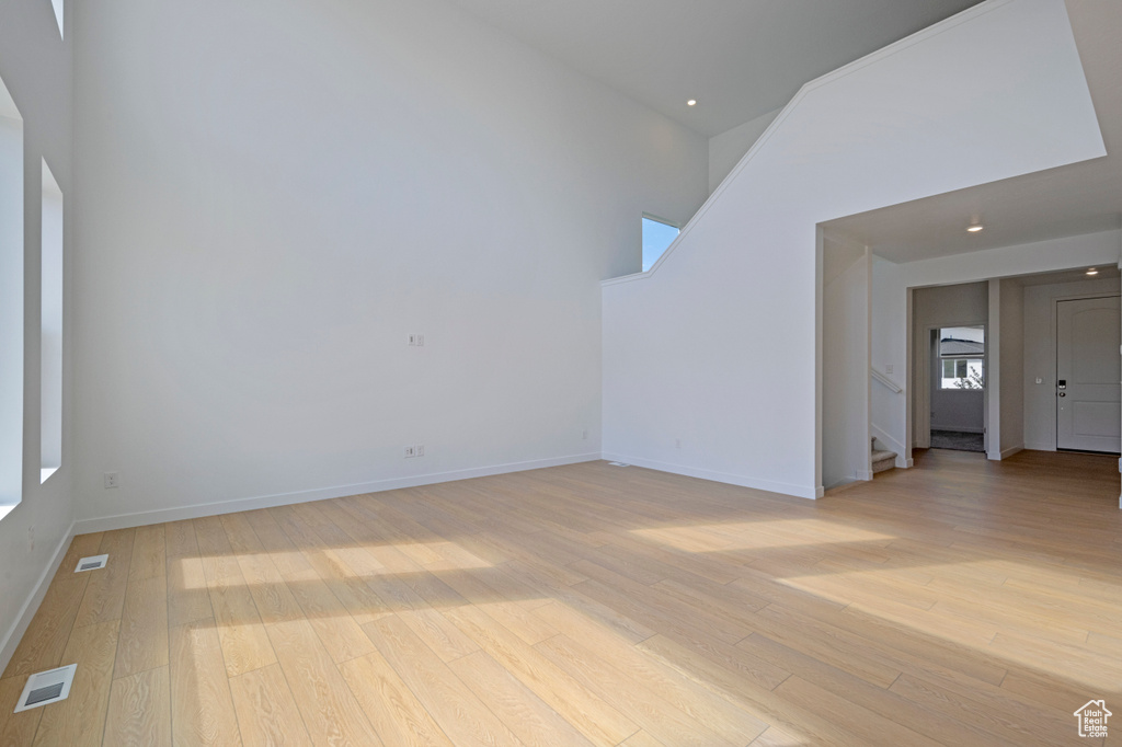 Unfurnished living room featuring stairs, light wood-style floors, plenty of natural light, and recessed lighting
