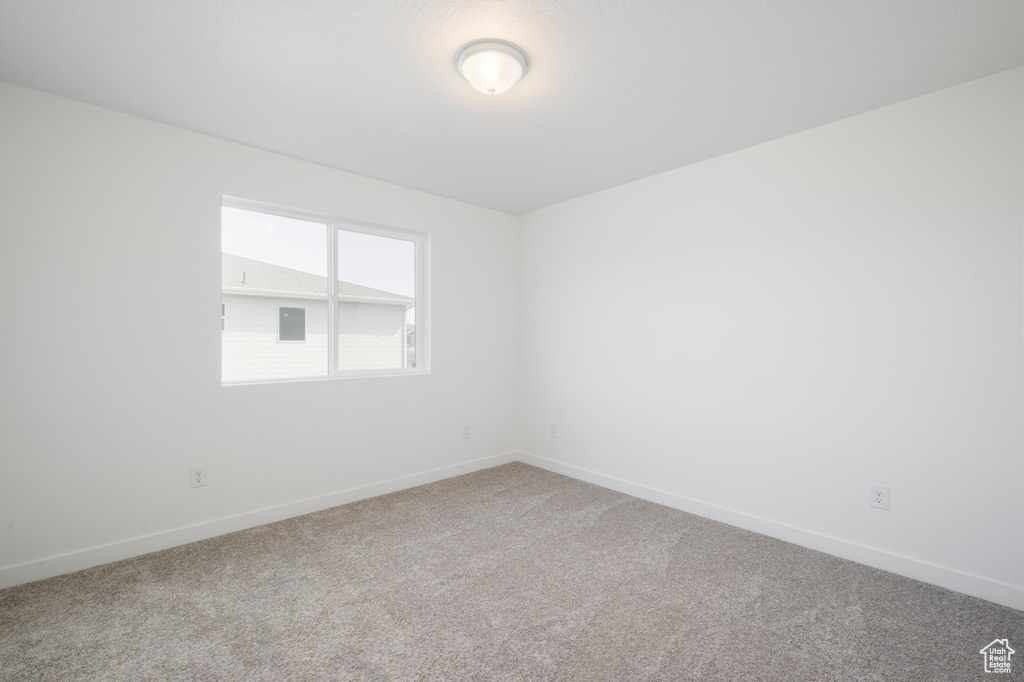 Carpeted spare room featuring baseboards