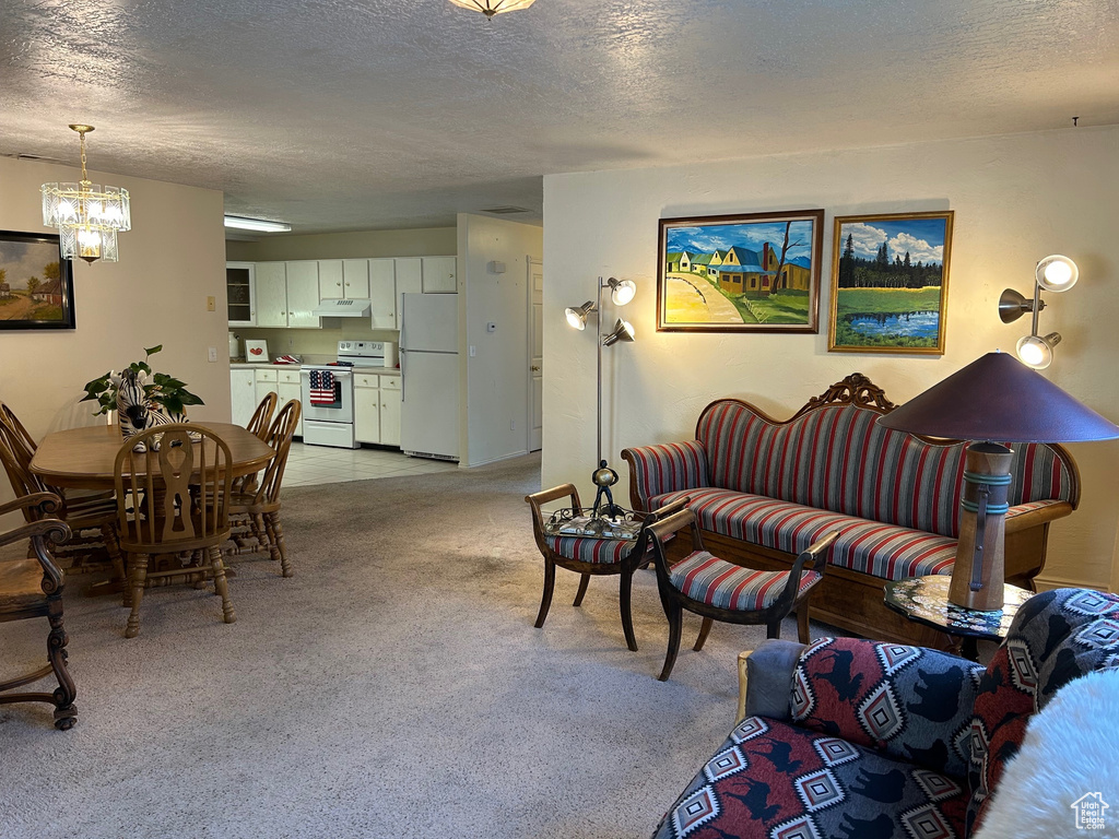 Living area featuring a textured ceiling, a chandelier, and light colored carpet