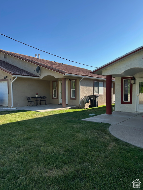 Rear view of property featuring stucco siding, a yard, a patio area, and a tiled roof