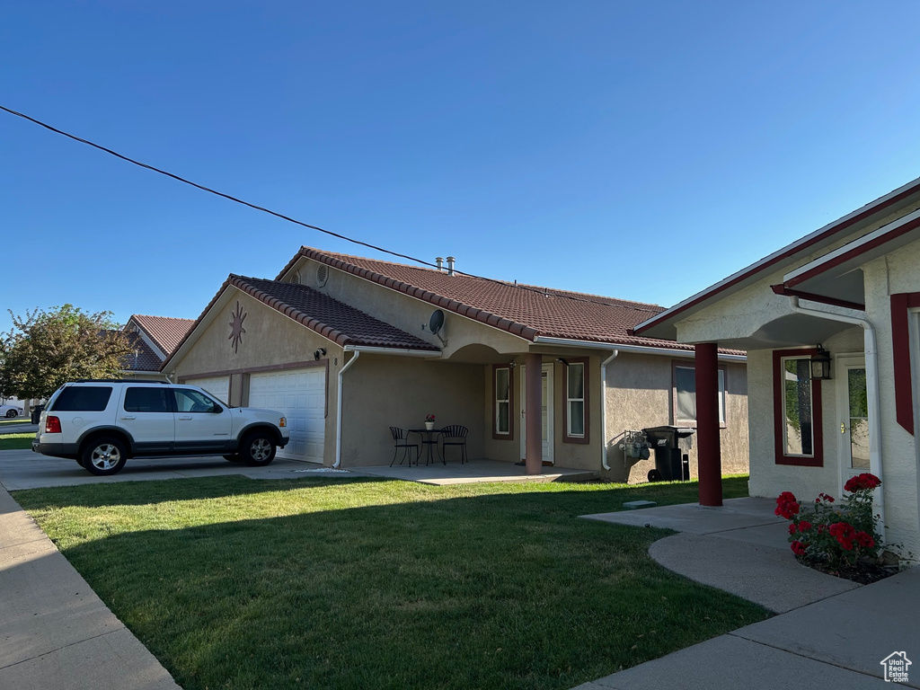 View of side of home with a garage, stucco siding, a lawn, and a tiled roof