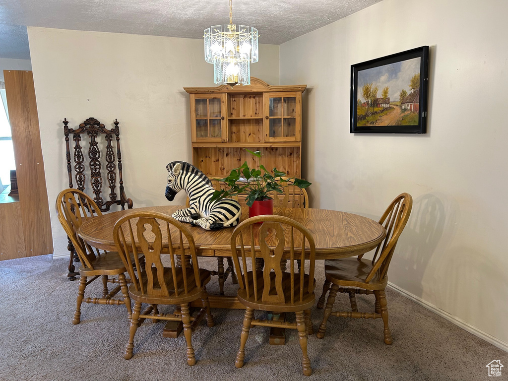 Dining area featuring carpet flooring, a chandelier, a textured ceiling, and baseboards