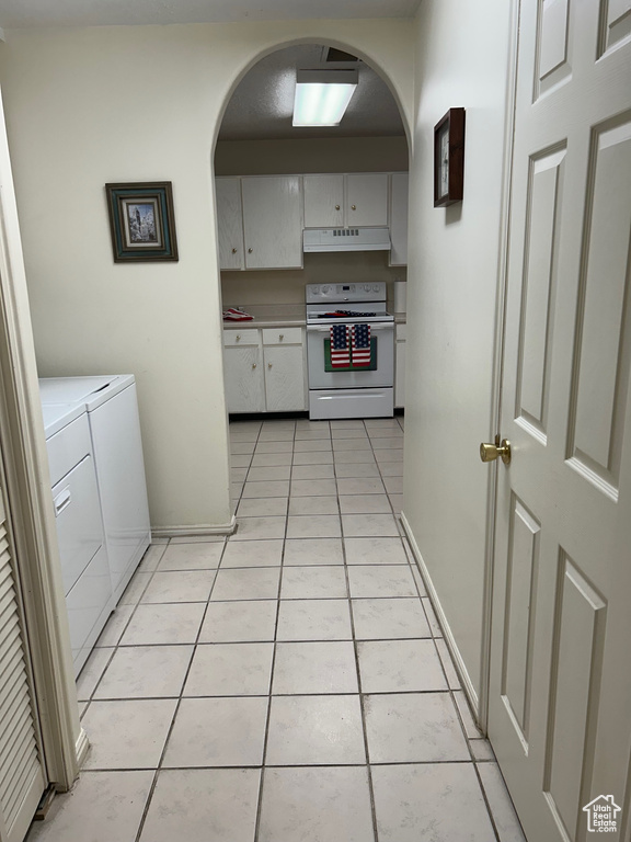 Kitchen featuring white range with electric cooktop, washing machine and dryer, arched walkways, and under cabinet range hood
