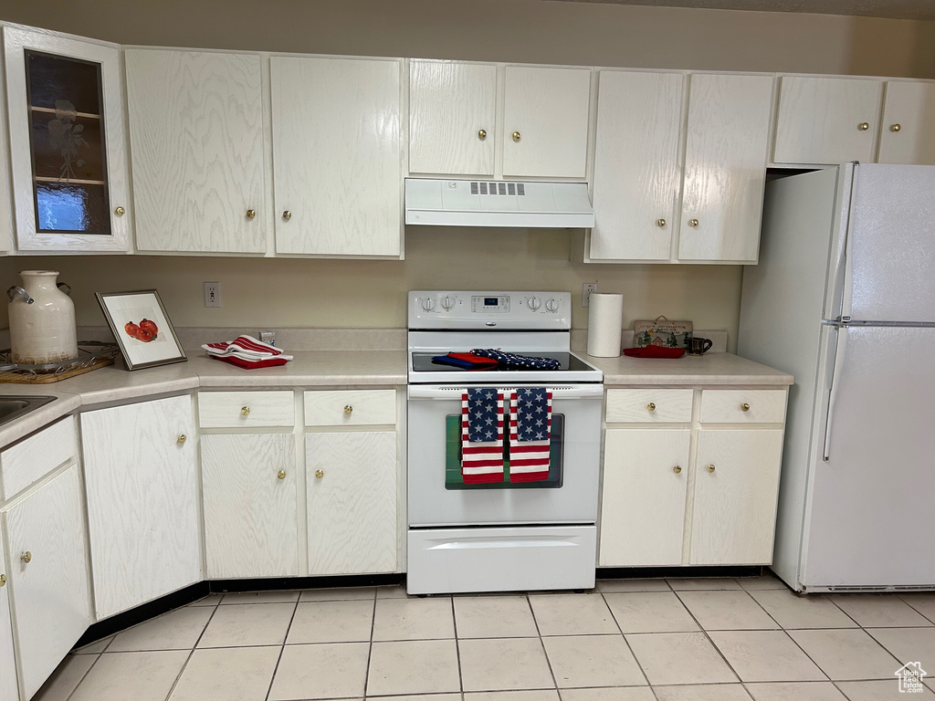 Kitchen with range hood, white appliances, light countertops, and light tile patterned flooring