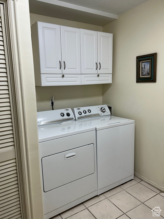 Laundry area with cabinet space, washing machine and clothes dryer, light tile patterned floors, and baseboards