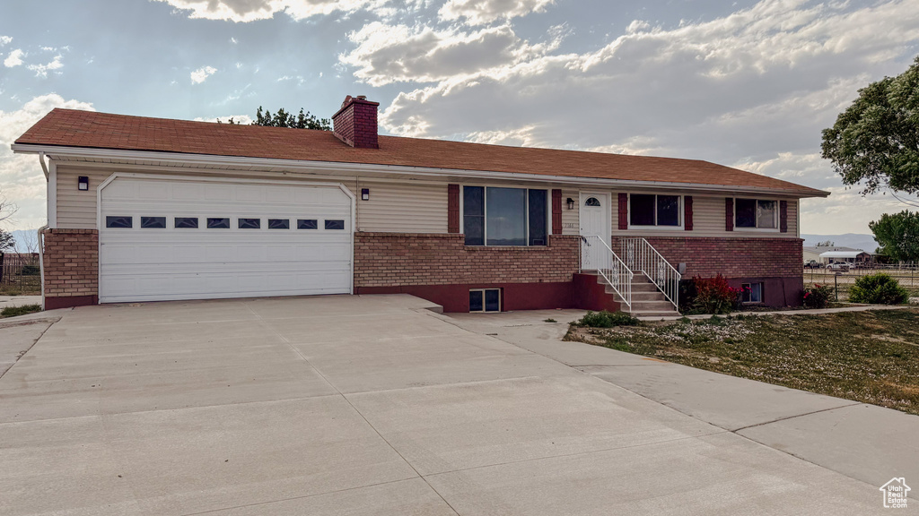 Single story home featuring brick siding, a chimney, concrete driveway, and a garage