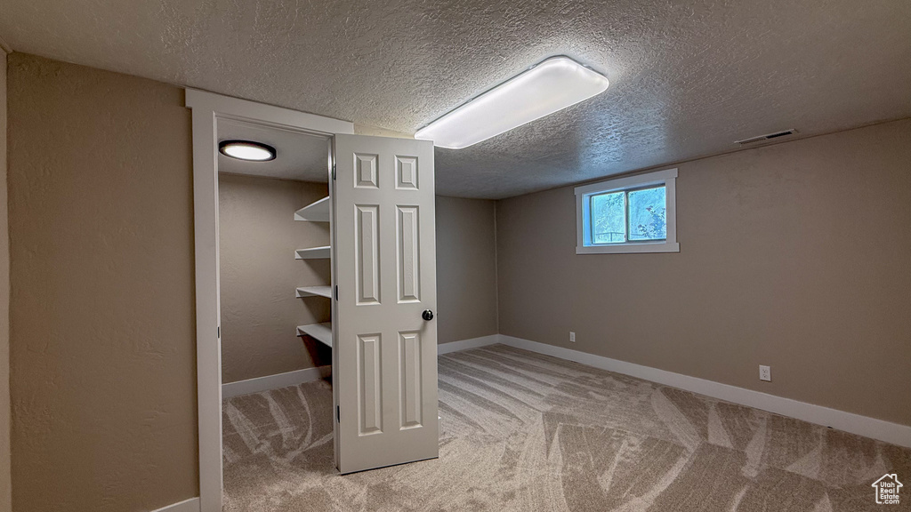 Below grade area featuring a textured ceiling and carpet