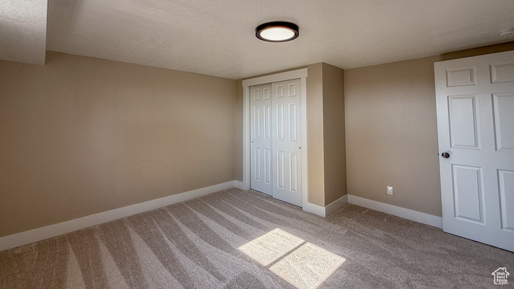 Unfurnished bedroom featuring light carpet, a closet, and a textured ceiling