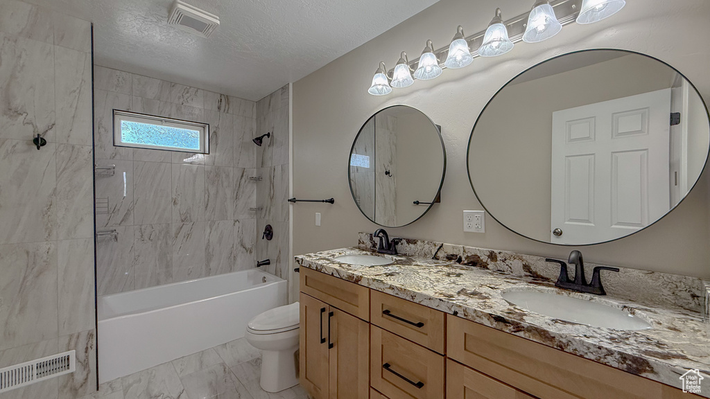 Full bath featuring double vanity, shower / bathtub combination, marble look tiles, and a textured ceiling