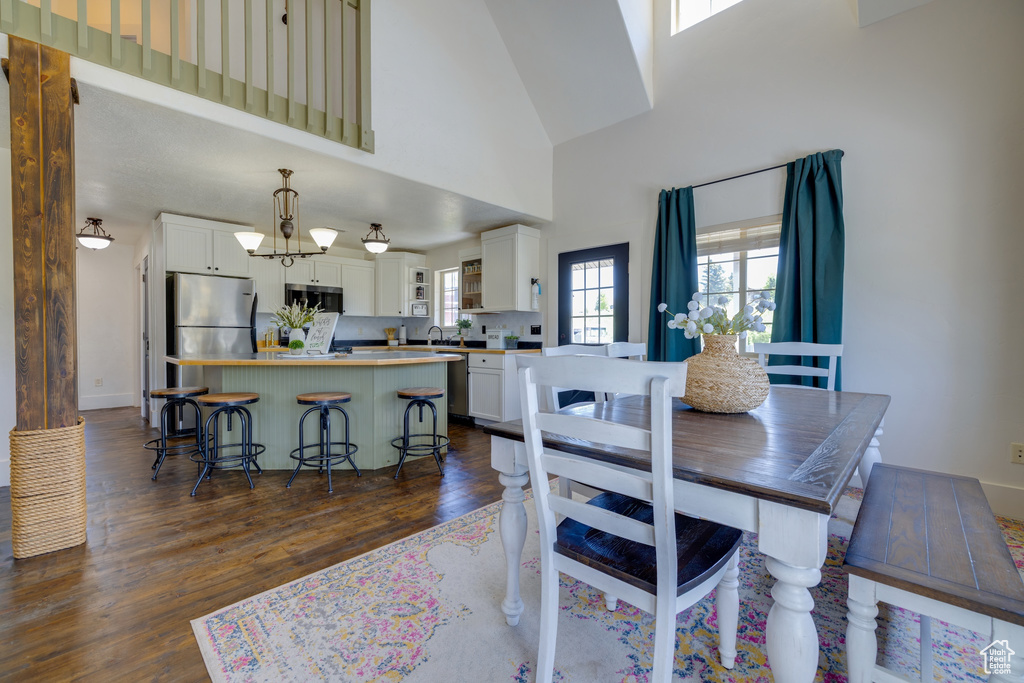 Dining area with dark wood-type flooring and a towering ceiling