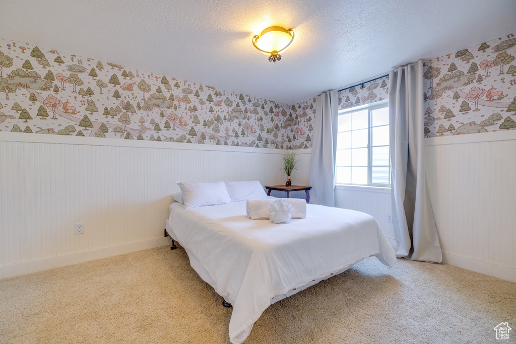 Bedroom featuring a wainscoted wall, wallpapered walls, and carpet