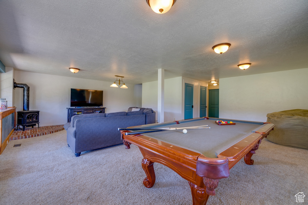 Game room with light carpet, a wood stove, a textured ceiling, and billiards