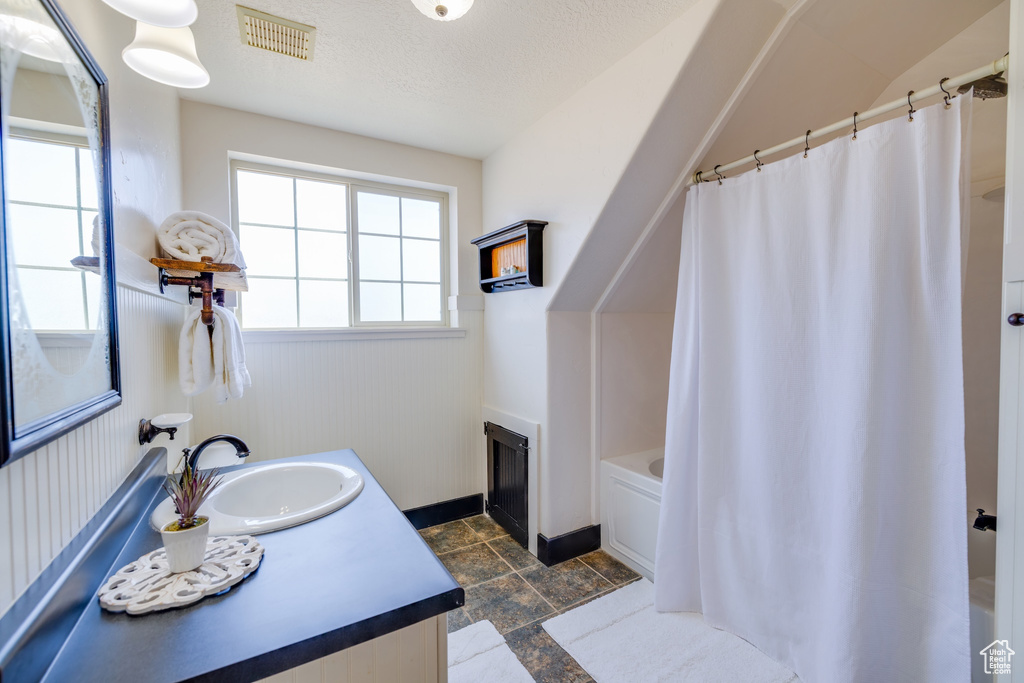 Full bathroom with vanity, a wainscoted wall, shower / tub combo with curtain, and stone finish flooring
