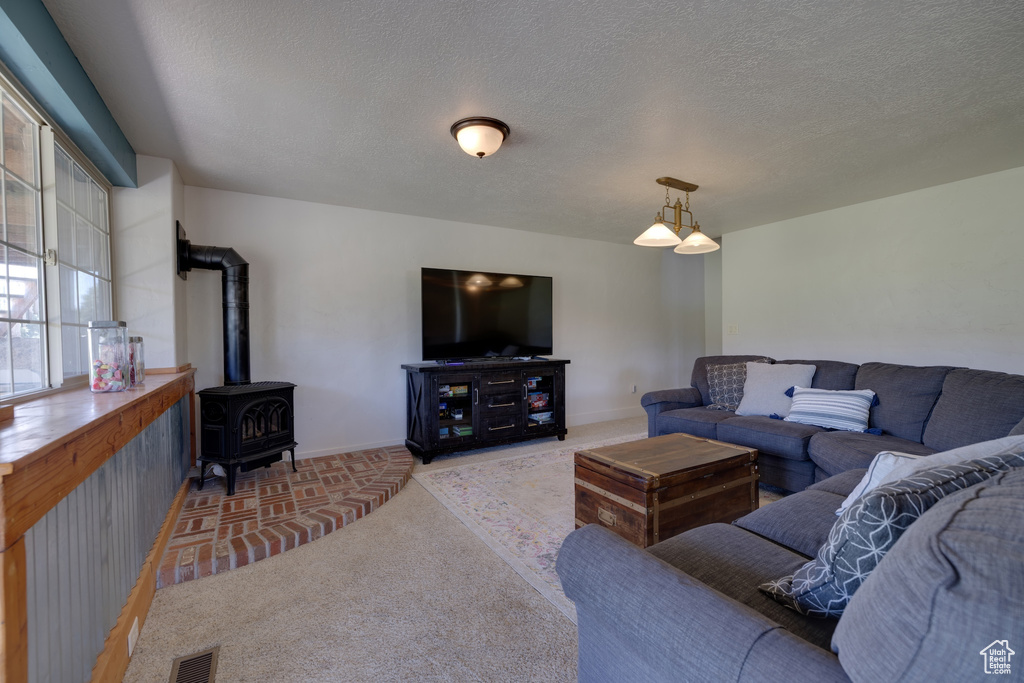Living area with a wood stove, carpet flooring, and a textured ceiling