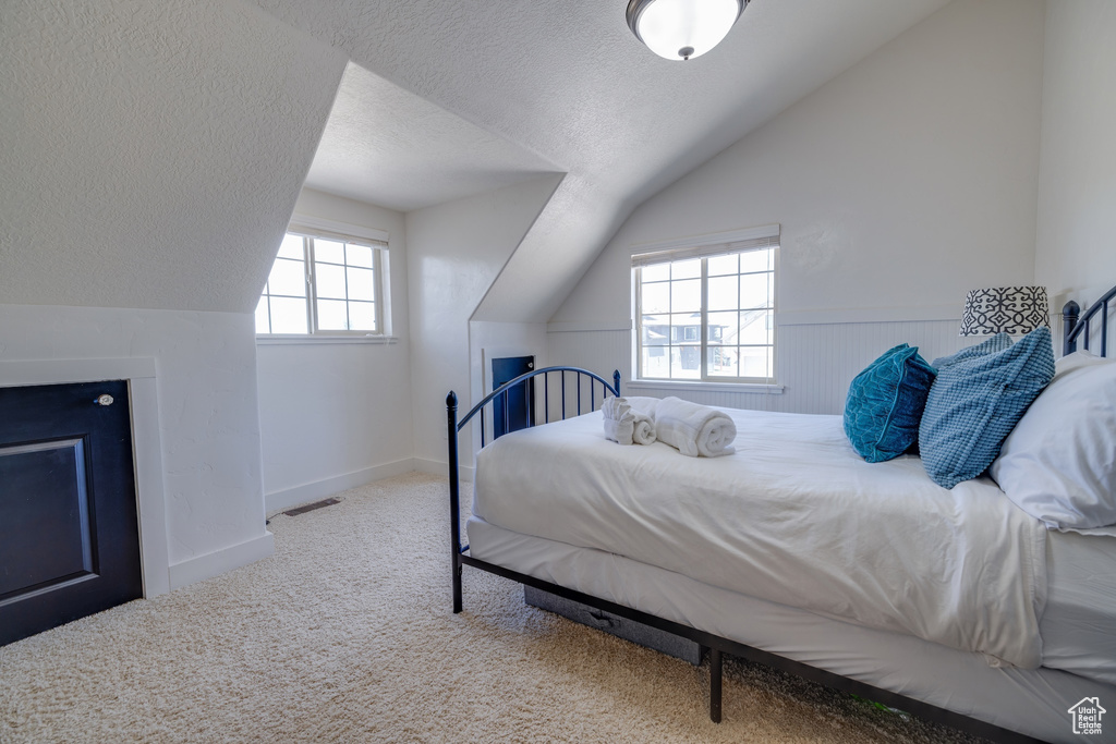 Bedroom featuring lofted ceiling, a textured ceiling, and carpet floors